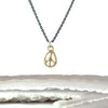 A gold peace sign pendant necklace on a dark gunmetal chain, with a  salt and pepper diamond accent