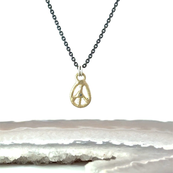 A gold peace sign pendant necklace on a dark gunmetal chain, with a  salt and pepper diamond accent
